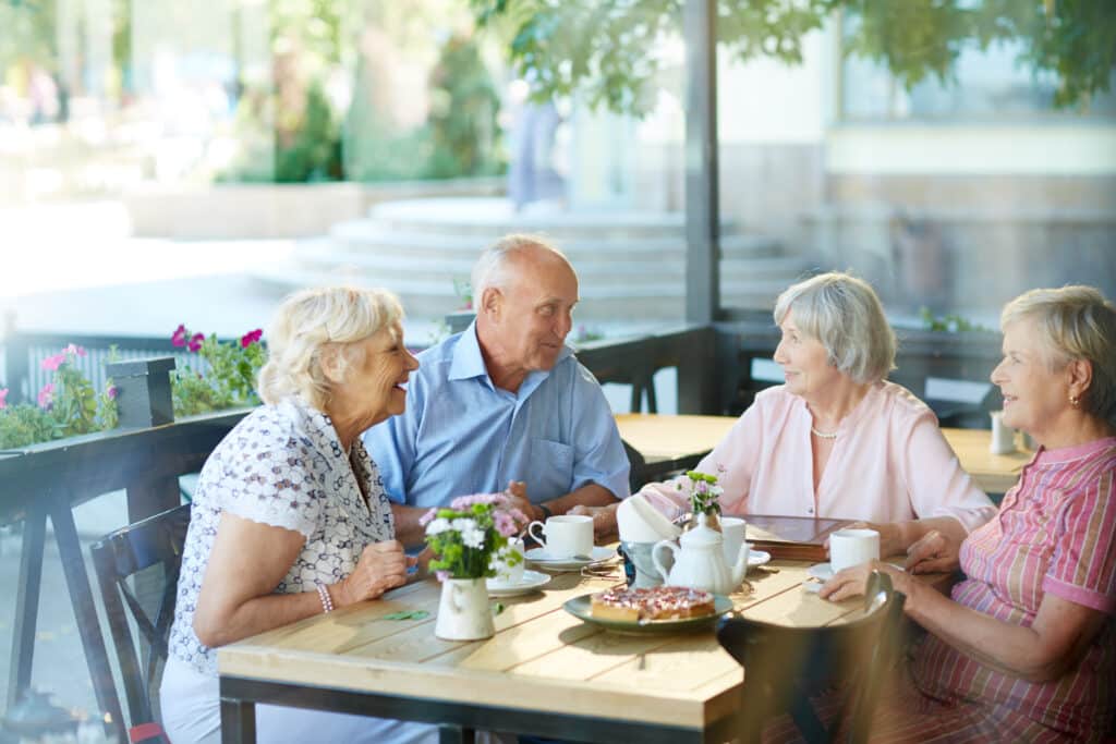 Groupe de seniors prenant un café ensemble à l'extérieur, illustrant la convivialité et la qualité de vie en EHPAD.