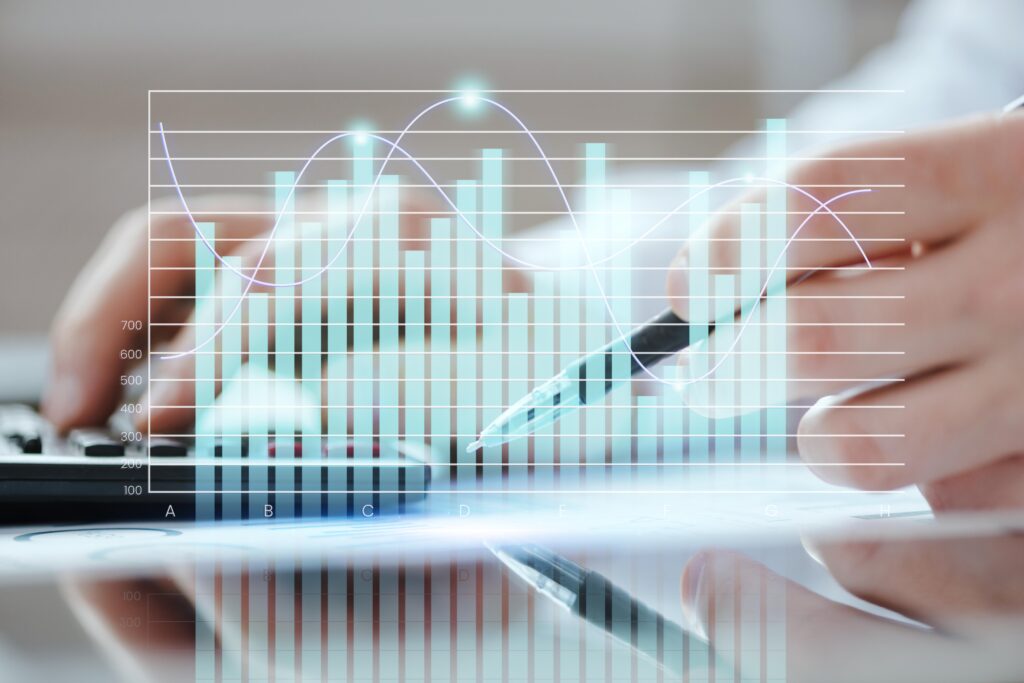 Des mains tenant un stylo et utilisant une calculatrice avec des graphiques en arrière-plan, illustrant l'analyse financière.