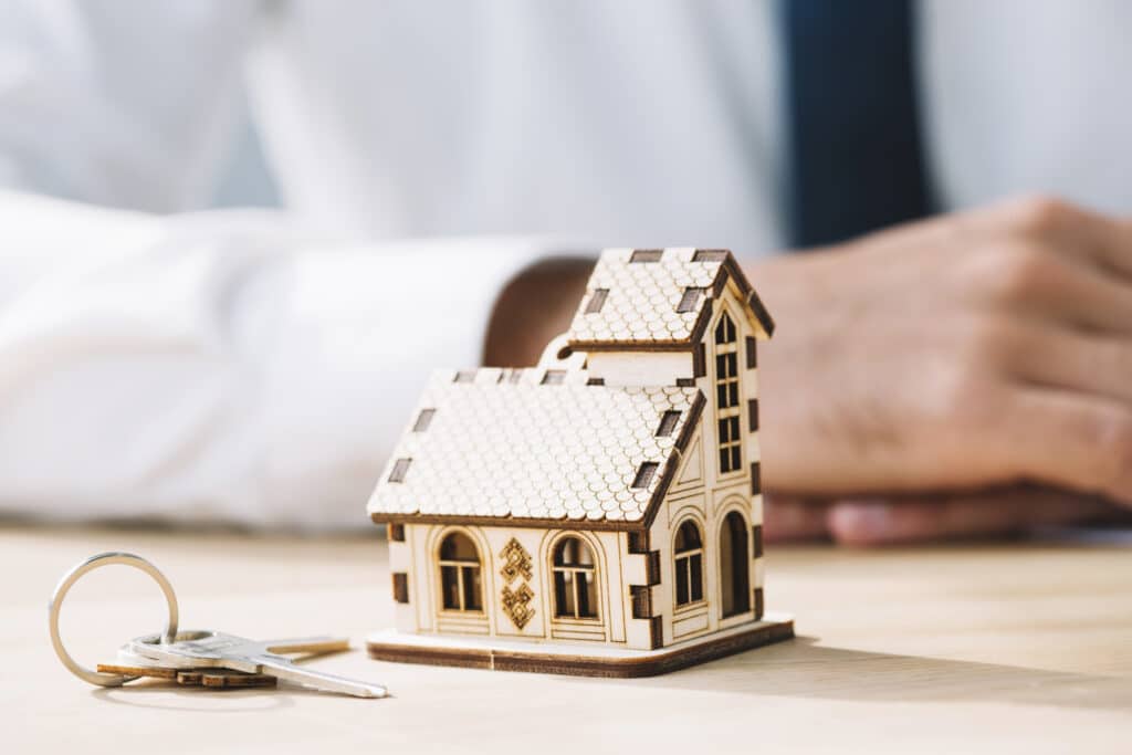 Maquette de maison et clés sur une table, symbolisant un investissement LMNP.